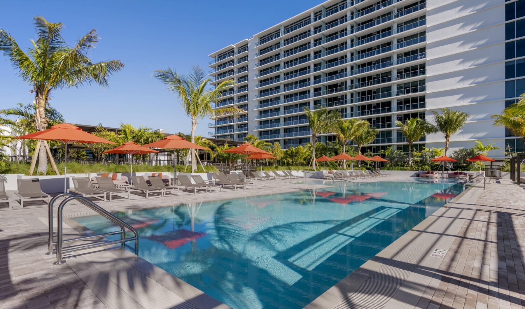 a pool with chairs and umbrellas by a building