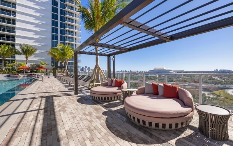 a deck with a lounge chair and a pool and a building