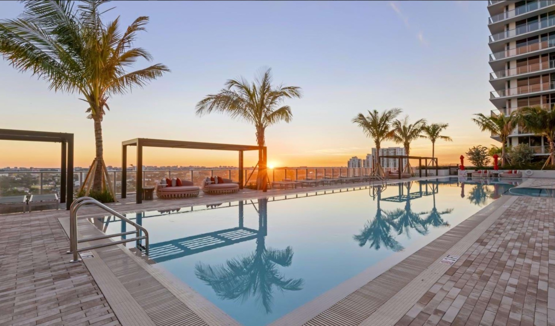 a pool with chairs and umbrellas by a building