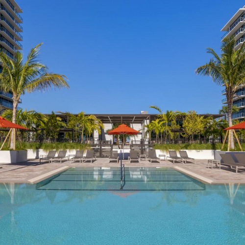 Shimmering resort-style pool a pool with lounge chairs and umbrellas by a building