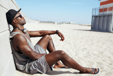Man sunbathing on the beach with headphones