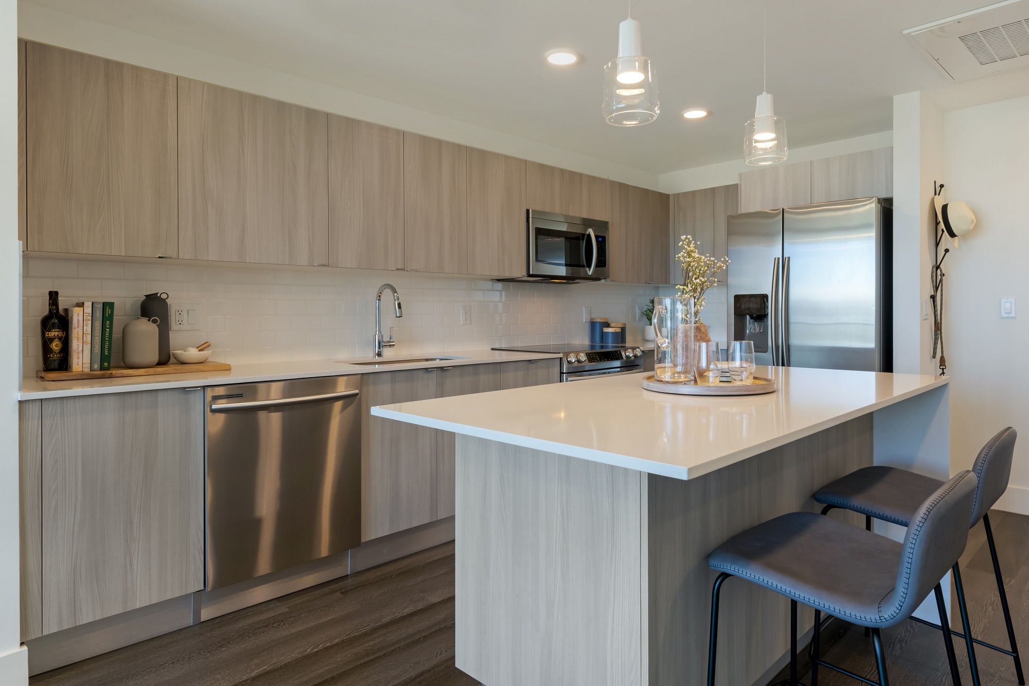 Open concept kitchen with quartz countertops, kitchen island with bar seating, designer lighting, and tile backsplash